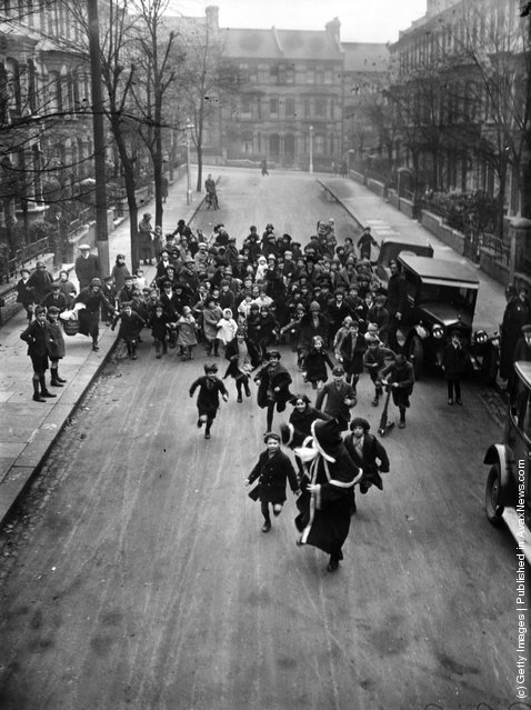 1926: A crowd of happy youngsters chase Father Christmas along a London street. He is on his way to a south London store to distribute presents